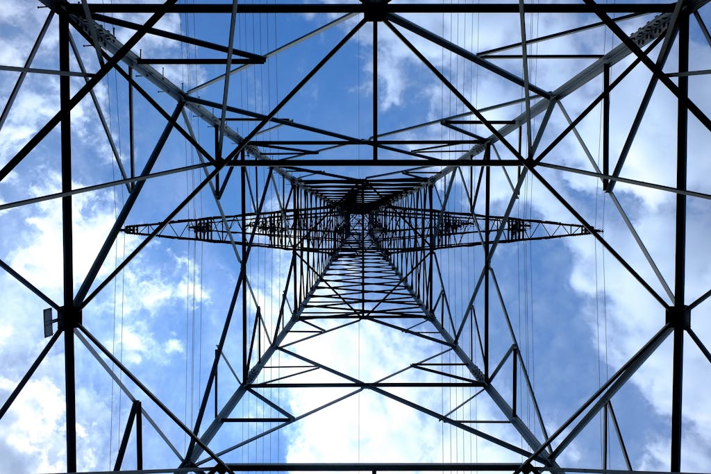 Looking up at a steel power pylon against a bright blue sky.